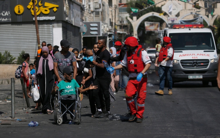 epa10725220 Members of Palestine Red Crescent Society (PRCS) help refugees to evacuate Jenin Camp to a safe place during the second day of an Israeli military operation in the camp of Jenin, West Bank, 04 July 2023. The Israeli army stated on 03 July that they launched a large-scale operation in Jenin. According to the Palestinian Health Ministry, at least ten people were killed and dozens of others wounded in the raid, adding that the death toll was likely to rise. EPA-EFE/ALAA BADARNEH