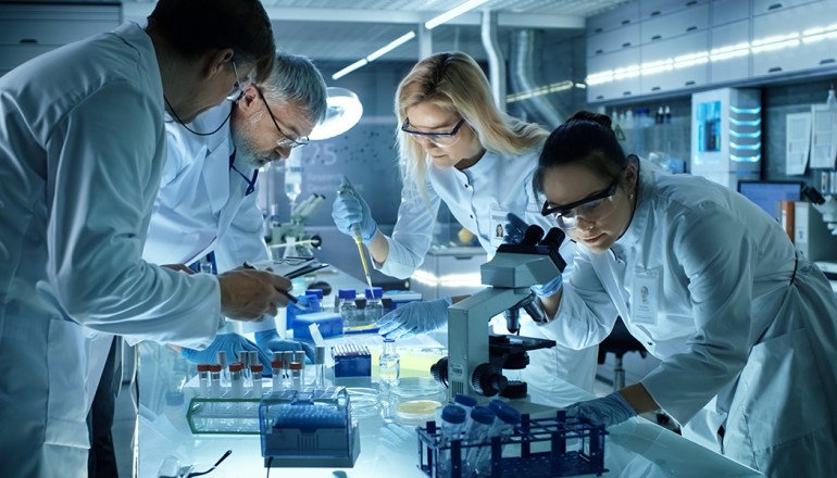 Team of Medical Research Scientists Collectively Working on a New Generation Experimental Drug Treatment. Laboratory Looks Busy, Bright and Modern.