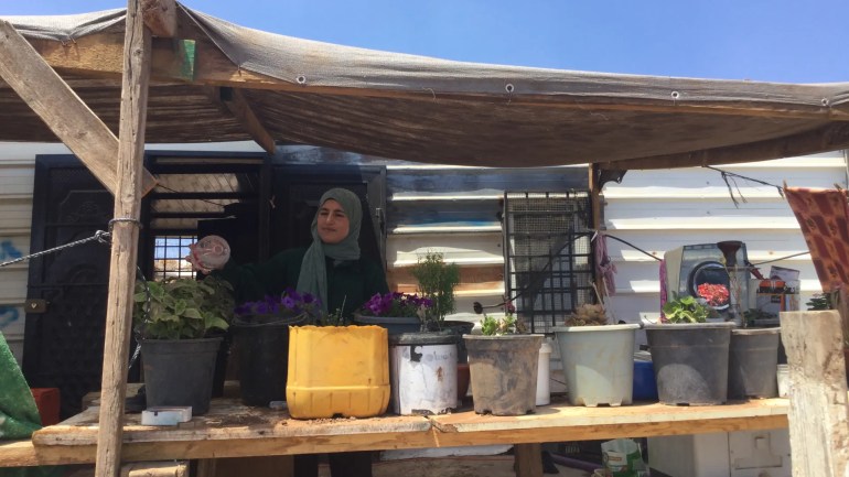 Ekhlas Kaabneh waters her plants in her home. An illegal settlement is close by, forcing Ekhlas to reinforce her house with safety features [Faris Ka'abneh/Al Jazeera]