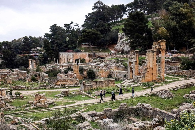 People walk through the remains of the Sanctuary of Apollo in the ruins of Libya's eastern ancient city of Cyrene, in the Jabal al-Akhdar region, on March 10, 2021. The spectacular ruins of the ancient Greek city of Cyrene survived Libya's 2011 revolution and an ensuing decade of lawlessness, but today they face new threats: plunder and bulldozers. Founded in the seventh century BC, Cyrene "was one of the principal cities in the Hellenic world", according to the UN's cultural agency UNESCO, which added the site to its World Heritage List in 1992. (Photo by Abdullah DOMA / AFP)