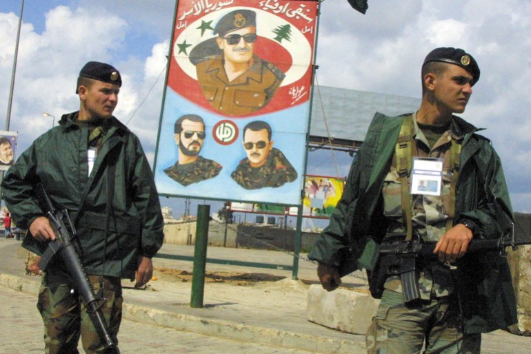 Lebanese soldiers stand guard in front of a billboard with images of late Syrian president Hafez al-Assad (Top) and his two sons Bashar (R), the current president and Basil (L), at the main road to Beirut's International airport as delegates attending the final day of the Arab summit begin to leave, 28 March 2002. The summit ended after adopting a ground-breaking proposal for collective Arab peace with Israel in return for the Jewish state's pullout from territory captured in the 1967 Arab-Israeli war. AFP PHOTO/Ramzi HAIDAR (Photo by RAMZI HAIDAR / AFP)