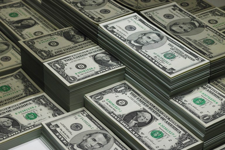 Piles of dollar bills reflected in glass - stock photo