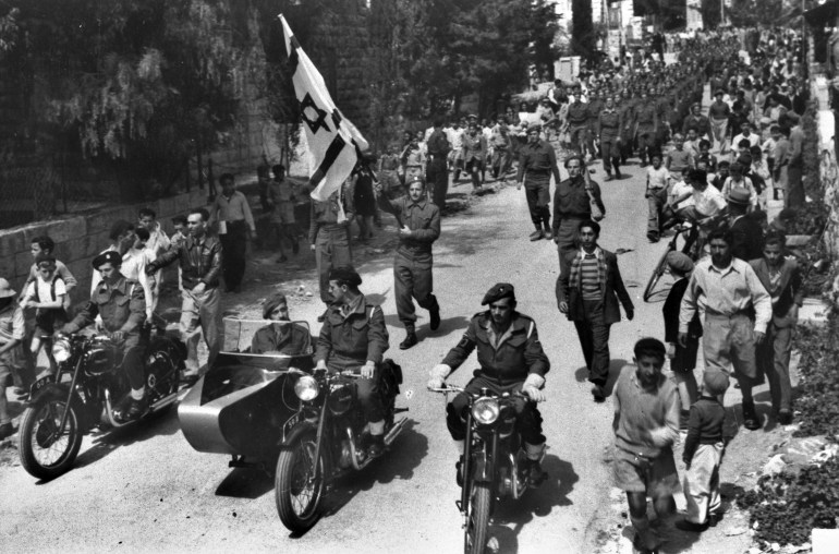 JERUSALEM, PALESTINE - APRIL 1, 1948: Fighters from the Haganah, the Jewish underground, parade with what would soon be the Israeli flag April 1, 1948, through the streets of Jewish Jerusalem in the British Mandate for Palestine. (Photo by GPO via Getty Images)