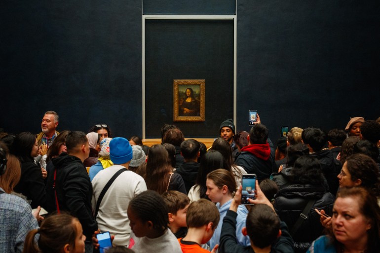 (FILES) Visitors take pictures of the painting "La Joconde" (The Mona Lisa) by Italian artist Leonardo Da Vinci at The Louvre Museum in Paris on January 23, 2025. French President Emmanuel Macron will next week visit the Louvre after the Paris museum's director issued a warning about the dire conditions for visitors and artefacts, the presidency said. The head of state will arrive at the Louvre on January 28, 2025, the Elysee said in a statement. (Photo by Dimitar DILKOFF / AFP) / RESTRICTED TO EDITORIAL USE - MANDATORY MENTION OF THE ARTIST UPON PUBLICATION - TO ILLUSTRATE THE EVENT AS SPECIFIED IN THE CAPTION