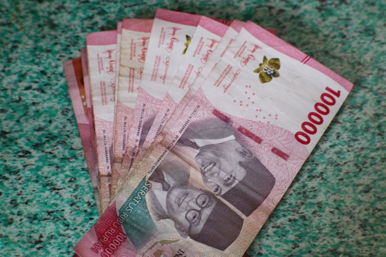 Close-up of a stack of Indonesian Rupiah (IDR) banknotes, featuring the portraits of Soekarno and Hatta. These one hundred thousand rupiah notes represent the currency of Indonesia and its financial system. المصدر: أدوبي ستوك