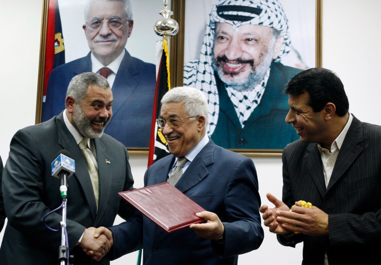 Palestinian President Mahmoud Abbas (C) gives the letter of appointment to Prime Minister Ismail Haniyeh (L) as senior Fatah leader Mohammed Dahlan watches in Gaza February 15, 2007. Abbas formally asked Haniyeh of Hamas on Thursday to form a new unity government and urged him to abide by peace accords signed with Israel. REUTERS/Suhaib Salem (GAZA)