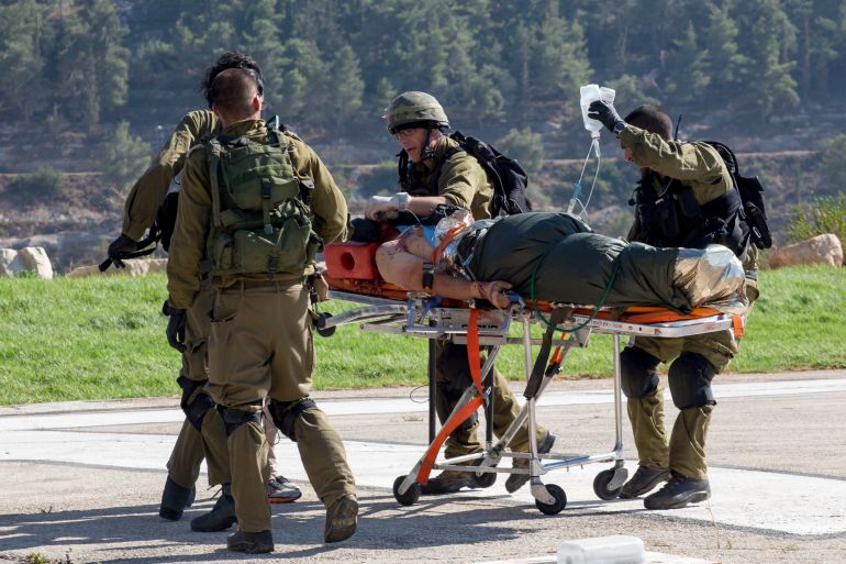 Israeli soldiers transport a wounded Israeli man to Hadassah Ein Kerem Hospital in Jerusalem after he was evacuated by helicopter, Thursday, Aug 6, 2015. A Palestinian motorist rammed his car into pedestrians near the West Bank Jewish settlement of Shilo, wounding three Israelis before he was shot by Israeli troops, the military said. (AP Photo/Emeil Salman) ****ISRAEL OUT***