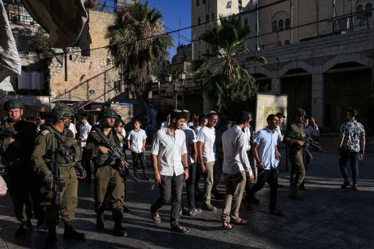 Israeli security forces stand guard as Israeli settlers tour in the Palestinian side of the old city and market of Hebron in the occupied West Bank on July 5, 2025. (Photo by HAZEM BADER / AFP)