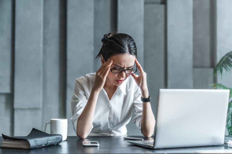 Young woman working on laptop having headache. Bored workaholic female accountant employee with headache and stress. Businesswoman woman with migraine, stress relief, chronic pain