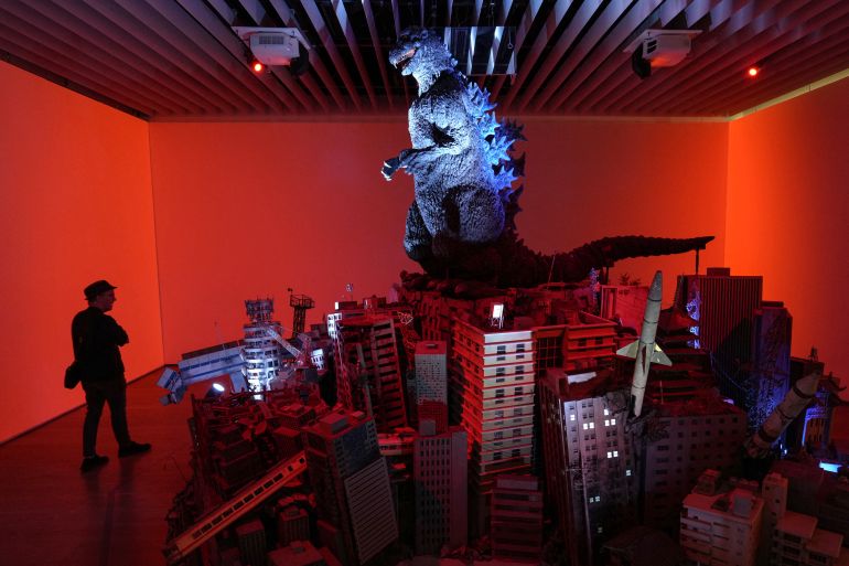 This photo taken on June 26, 2025 shows a man visiting the exhibition commemorating the 70th anniversary of Godzilla's birth, titled GODZILLA THE ART at Tokyo's Mori Arts Center Gallery. From Godzilla's fiery atomic breath to harrowing literary depictions of radiation sickness, the influence of the nuclear bombings of Hiroshima and Nagasaki runs deep in Japanese popular culture. (Photo by Kazuhiro NOGI / AFP) / TO GO WITH 'JAPAN-CULTURE-HISTORY-NUCLEAR-WWII' BY KATIE FORSTER AND KYOKO HASEGAWA --- RESTRICTED TO EDITORIAL USE - MANDATORY MENTION OF THE ARTIST UPON PUBLICATION - TO ILLUSTRATE THE EVENT AS SPECIFIED IN THE CAPTION