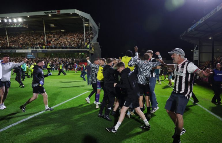 يحتفل مشجعو Grimsby Town على أرض الملعب بعد المباراة ضد Man UTD